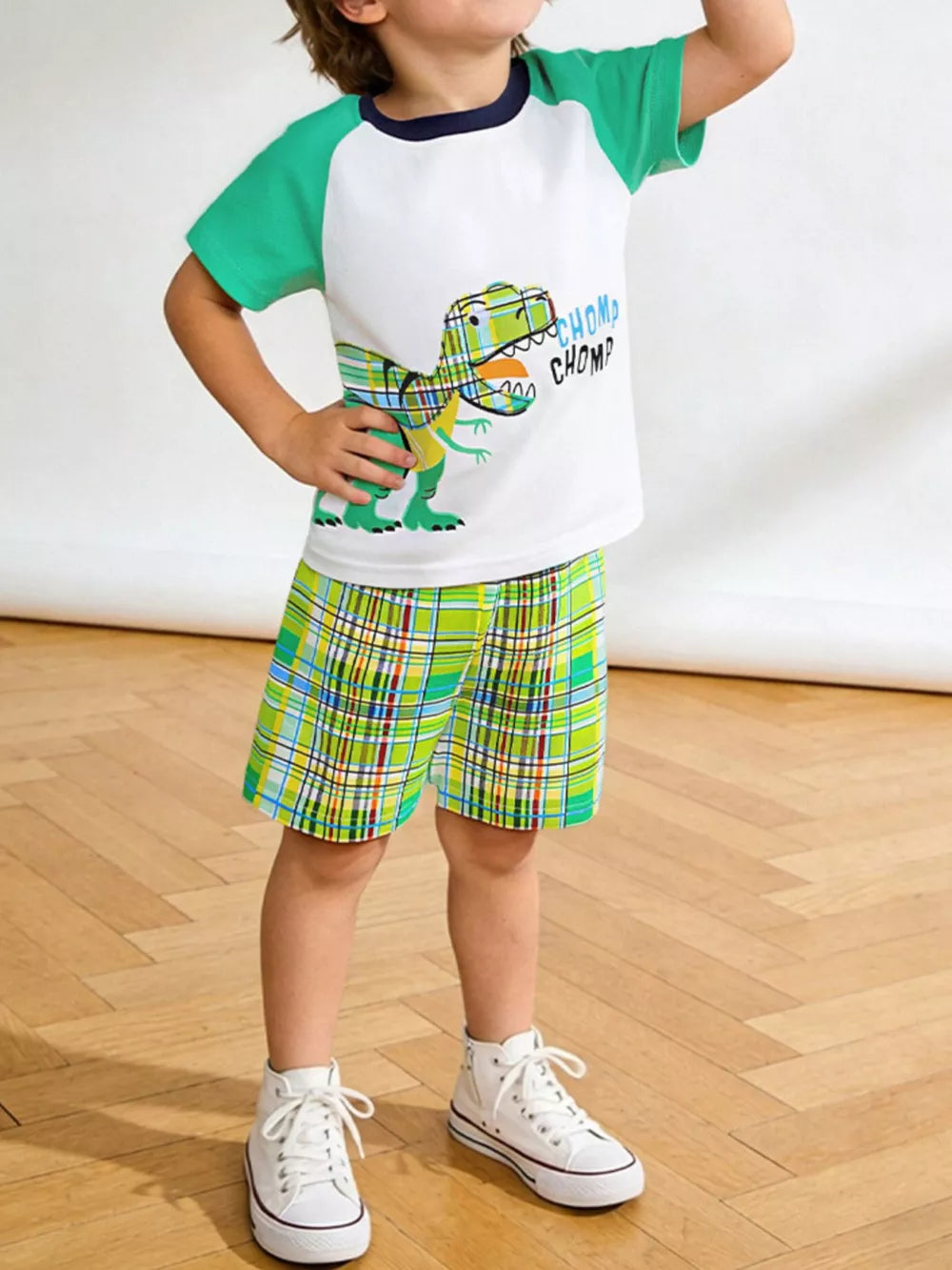 White t-shirt with dinosaur graphic and green plaid shorts