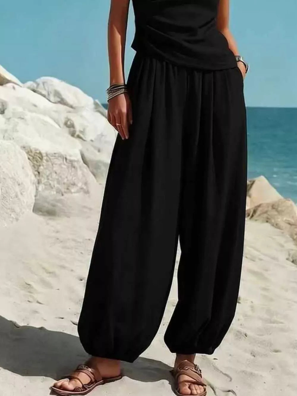 Black one-shoulder top and wide-leg pants set with pockets, styled with sandals.