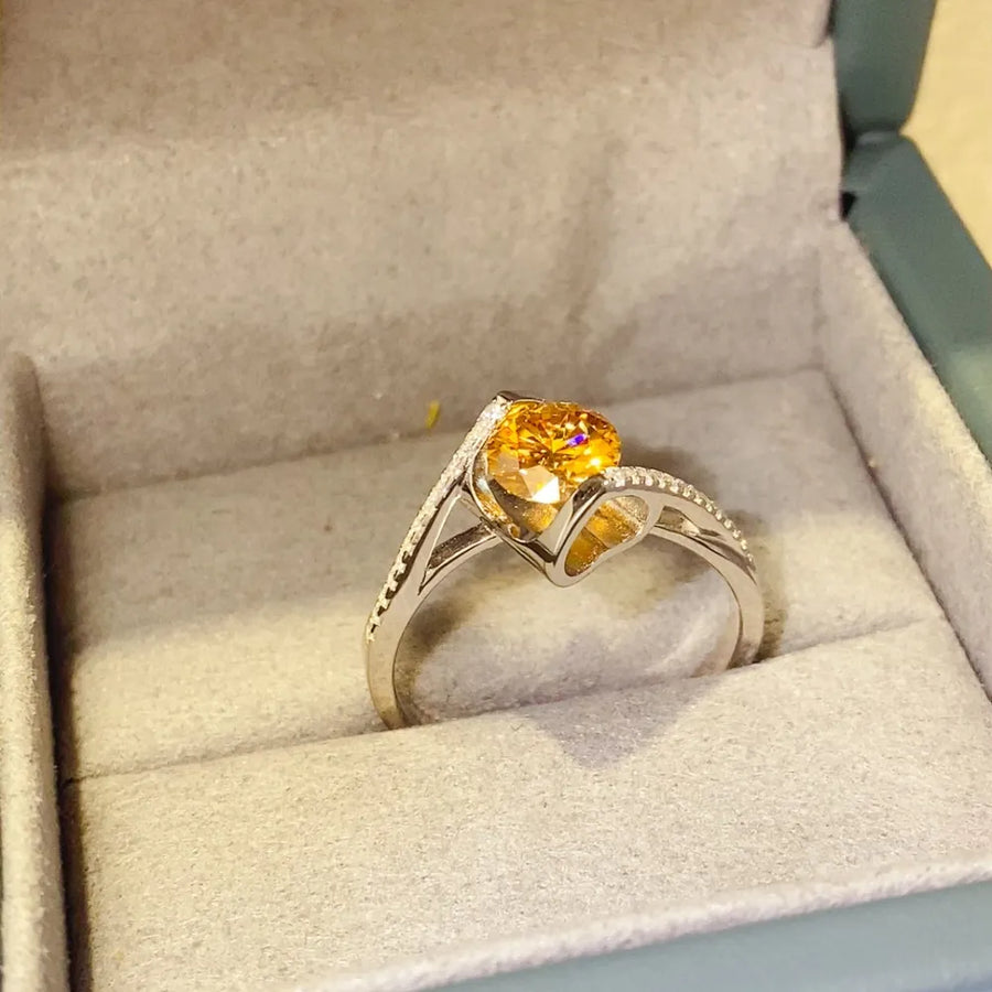 Silver twist ring with radiant yellow heart-shaped moissanite and diamond accents.