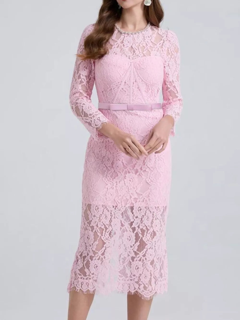 Pink lace midi dress with sheer sleeves, sweetheart neckline, and satin belt.