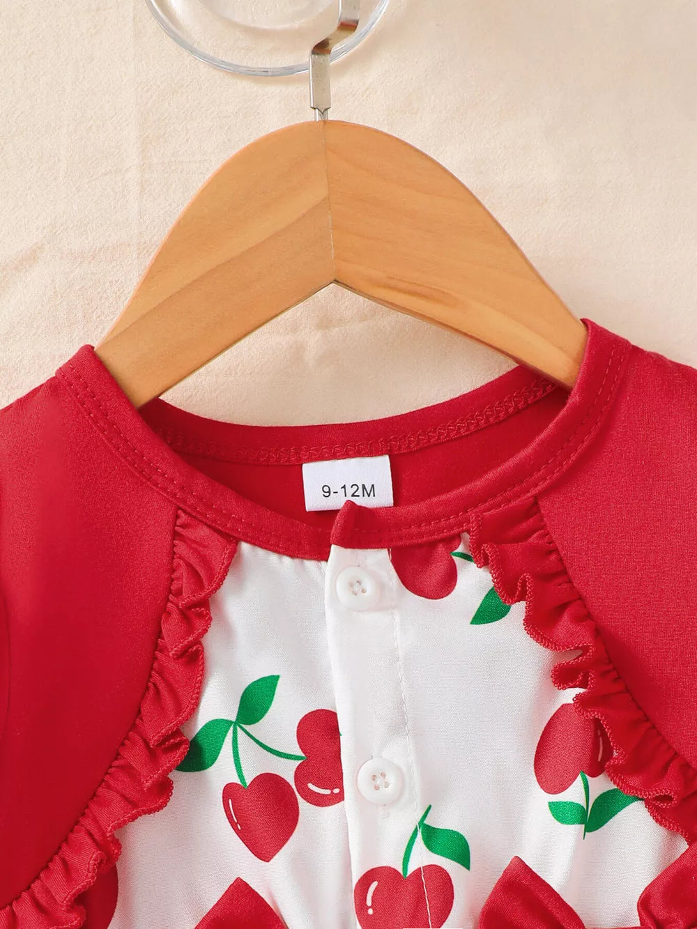 Baby dress with red cherry print, ruffled trim, and button front.