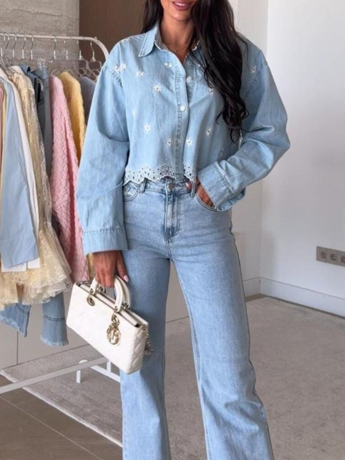 Light blue denim cropped shirt with floral embroidery and eyelet trim, worn by a woman.