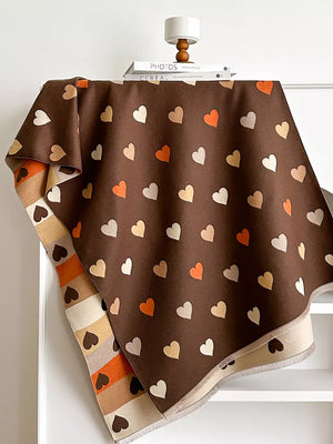 Brown scarf with scattered heart pattern in beige, white, and orange. Striped border detail.