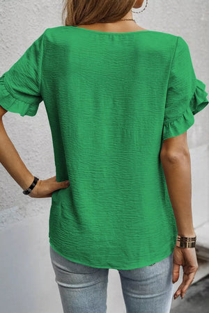 Green polyester blouse with short ruffled sleeves and textured fabric.