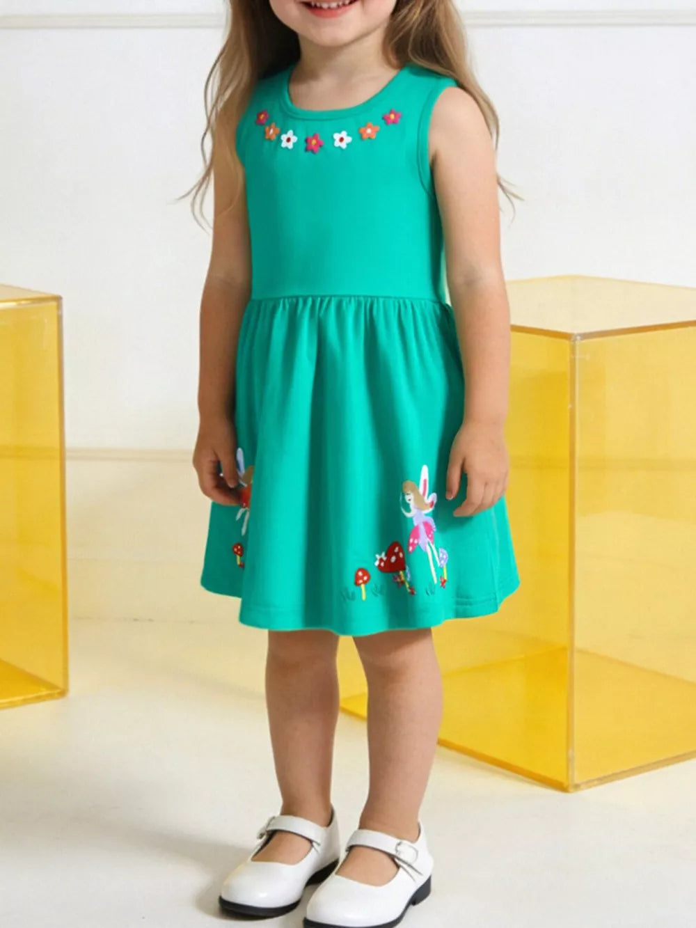 Green a-line dress with floral appliqué neckline and woodland print hem.