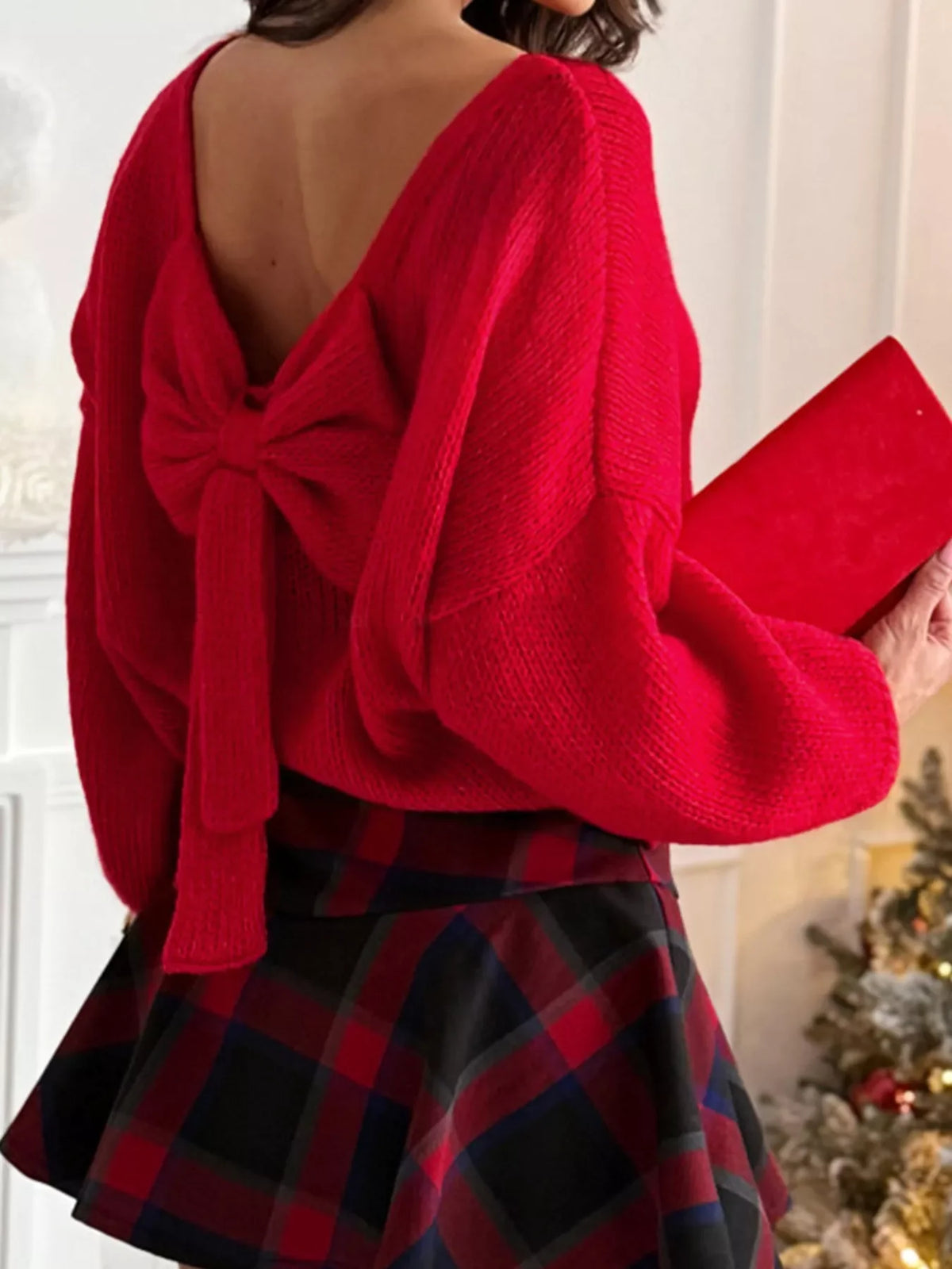 Red long-sleeve sweater with a large bow detail on the back, featuring a V-neckline.