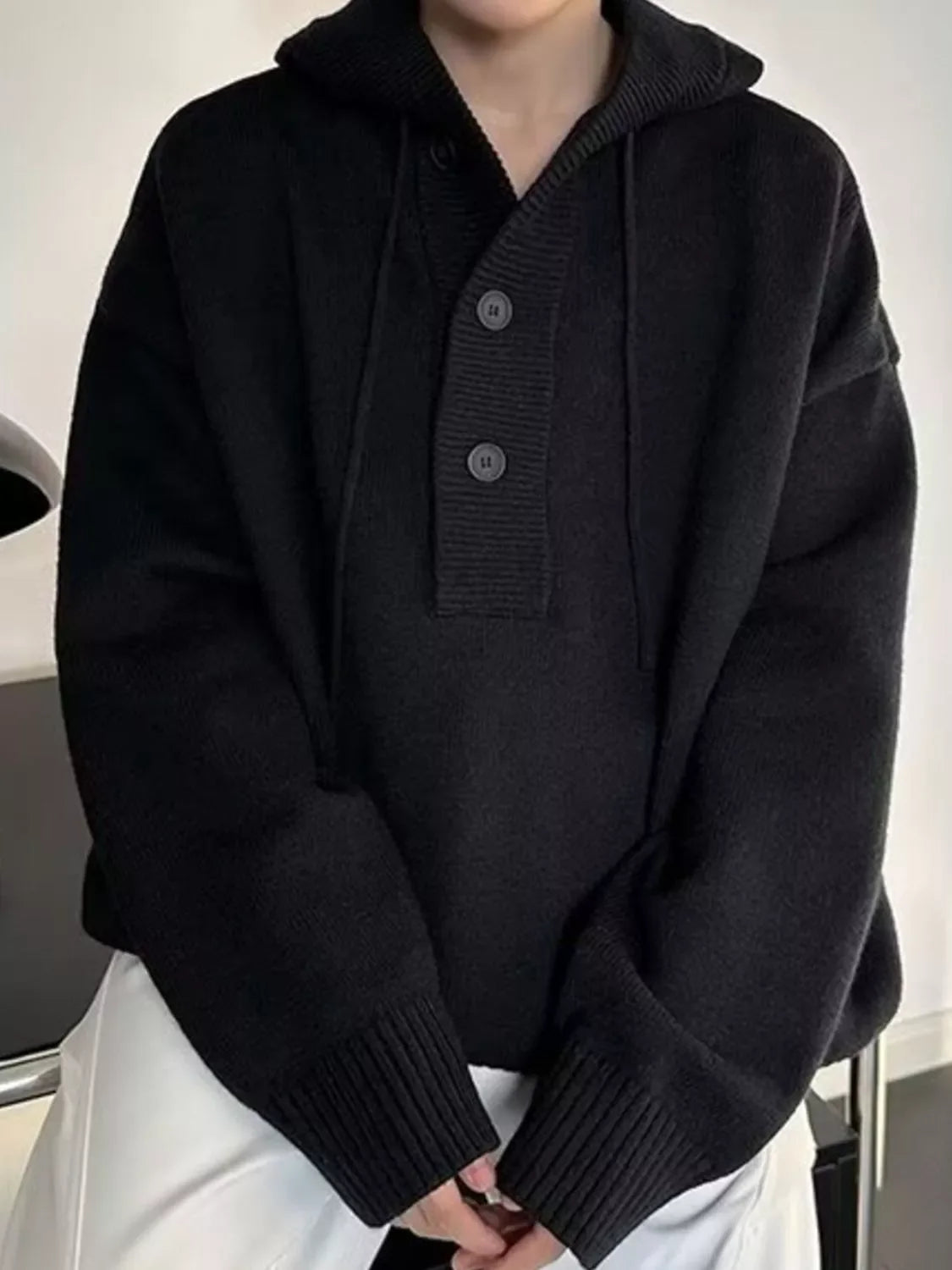 Black hooded knit sweater with button detail and drawstring.