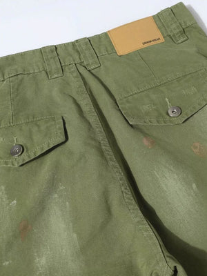 Green distressed cargo pants with button flap pockets and a leather patch detail.
