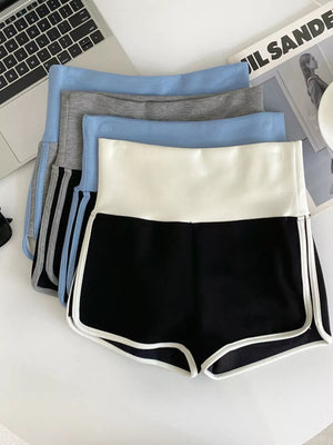 Black athletic shorts with white contrast trim and high-rise waist, layered with other colors.
