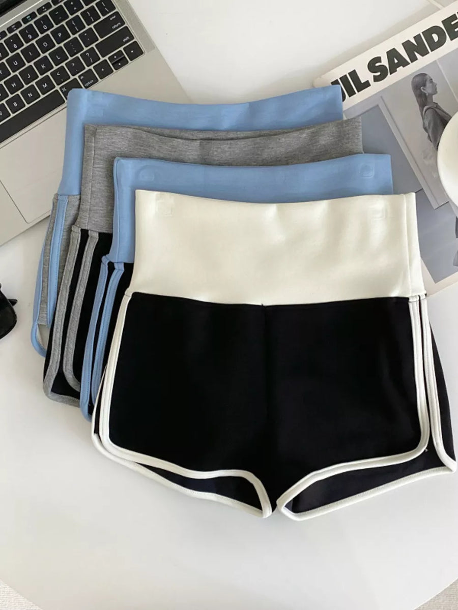 Black athletic shorts with white contrast trim and high-rise waist, layered with other colors.