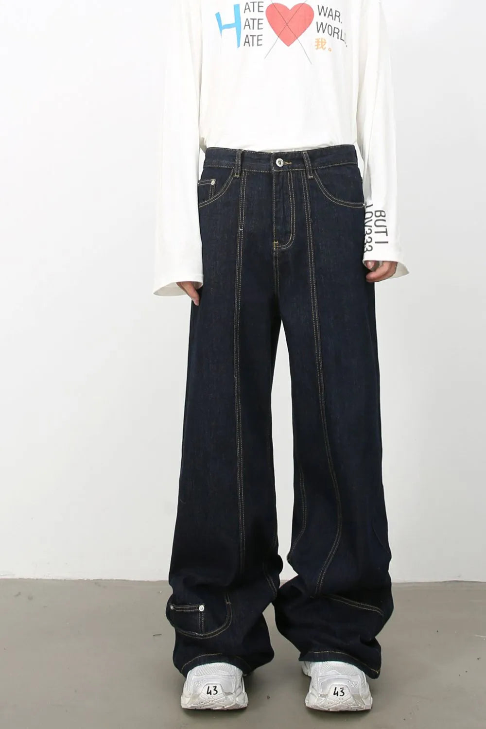 Dark denim wide-leg trousers with sculptural seam details and contrast stitching.