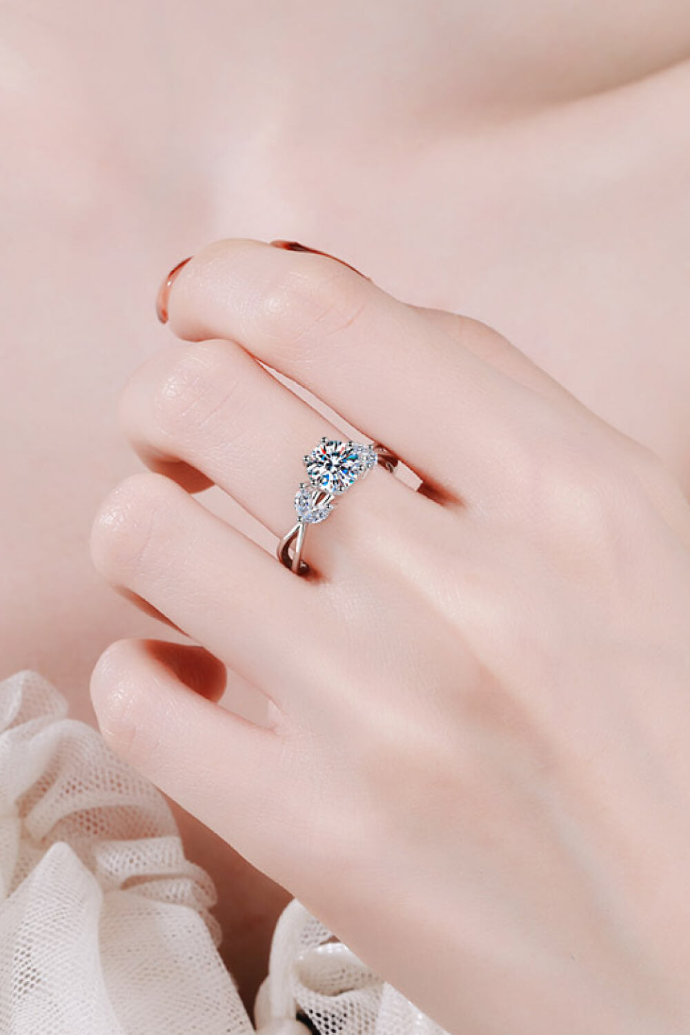Silver moissanite ring with a central round cut stone and leaf-shaped accents.