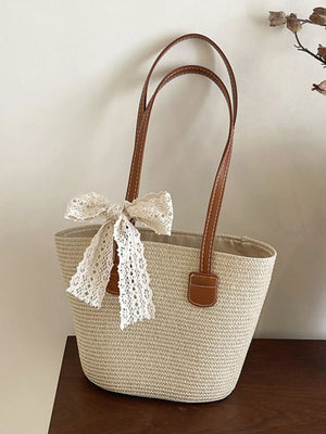 Charming straw shoulder bag in off-white with lace bow detail and brown leather straps.