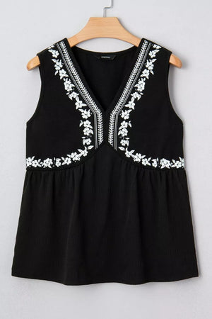 Black sleeveless V-neck top with white floral embroidery and textured fabric.