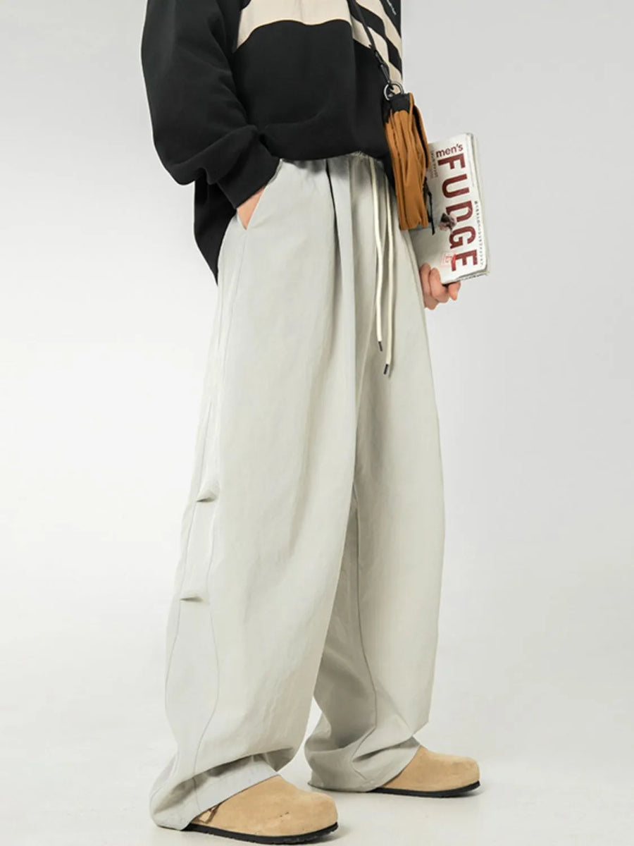 Light gray balloon-fit drawstring trousers with pleated front and side detail.