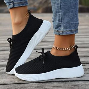Black lace-up sneakers with white mid sole and breathable knit upper.