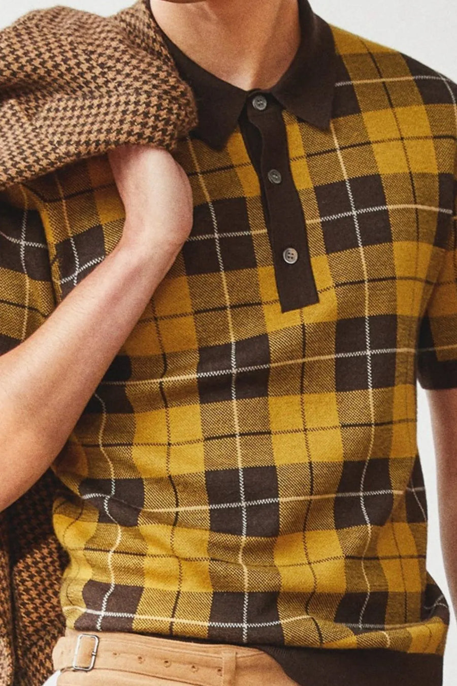 Checked knit polo with contrast trim in plaid, featuring a buttoned neckline and short sleeves.