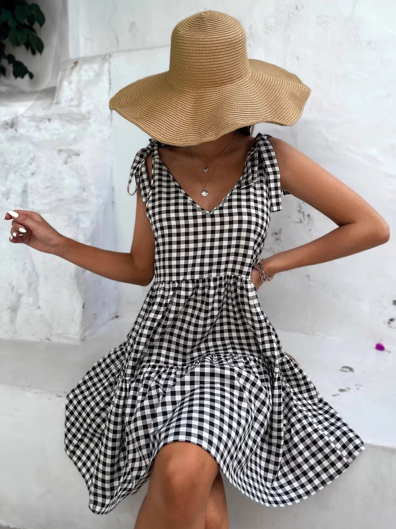Black and white gingham tie-shoulder mini dress with tiered skirt.