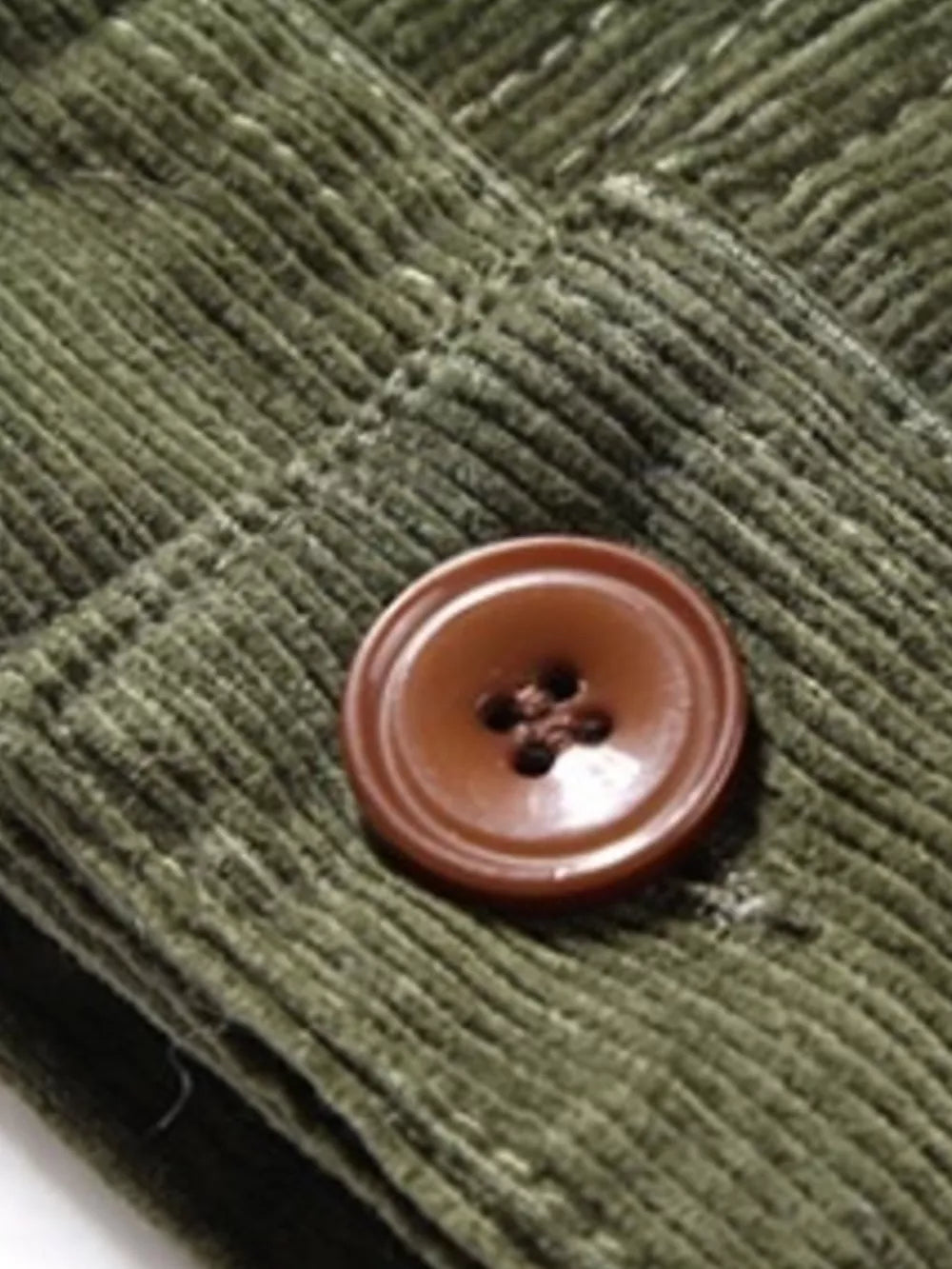 Army green corduroy jacket detail with a brown button closure.