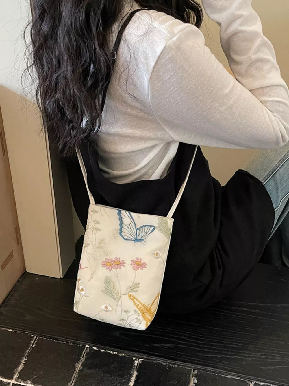 Delicate embroidered mini crossbody bag in off-white with butterfly and floral pattern.