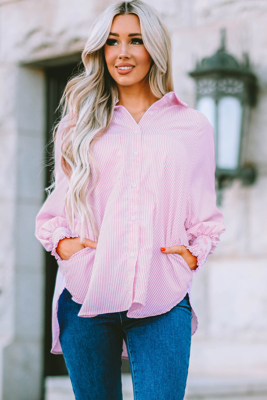 Blush pink pinstripe blouse with balloon sleeves and ruffled cuffs, worn by a model with jeans.