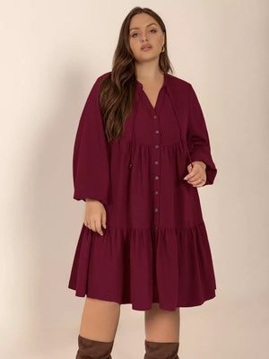 Plus-size burgundy button-front tiered dress with balloon sleeves and tie neckline.