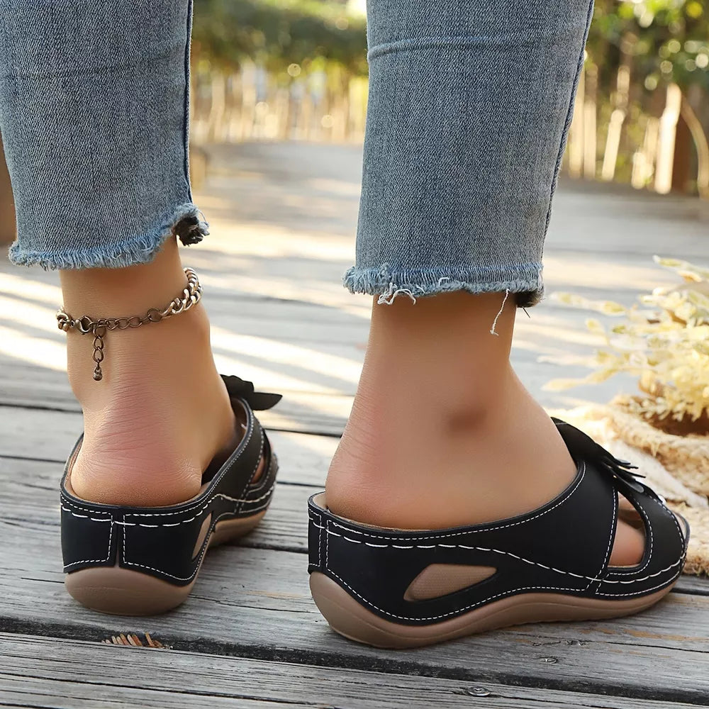 Black floral embellished mid-wedge sandals with white stitching and cut-out details.