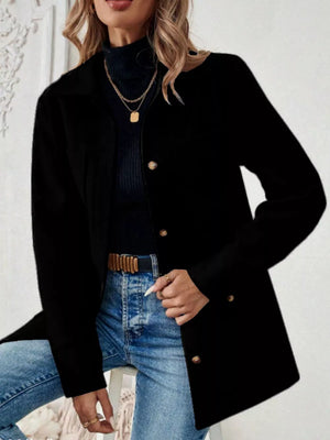 Black button-front trench coat with gold buttons and pockets, styled with jeans.