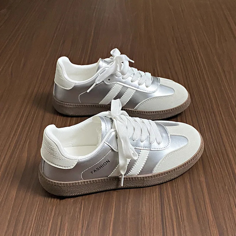Silver leather sneakers with white accents and branding detail.