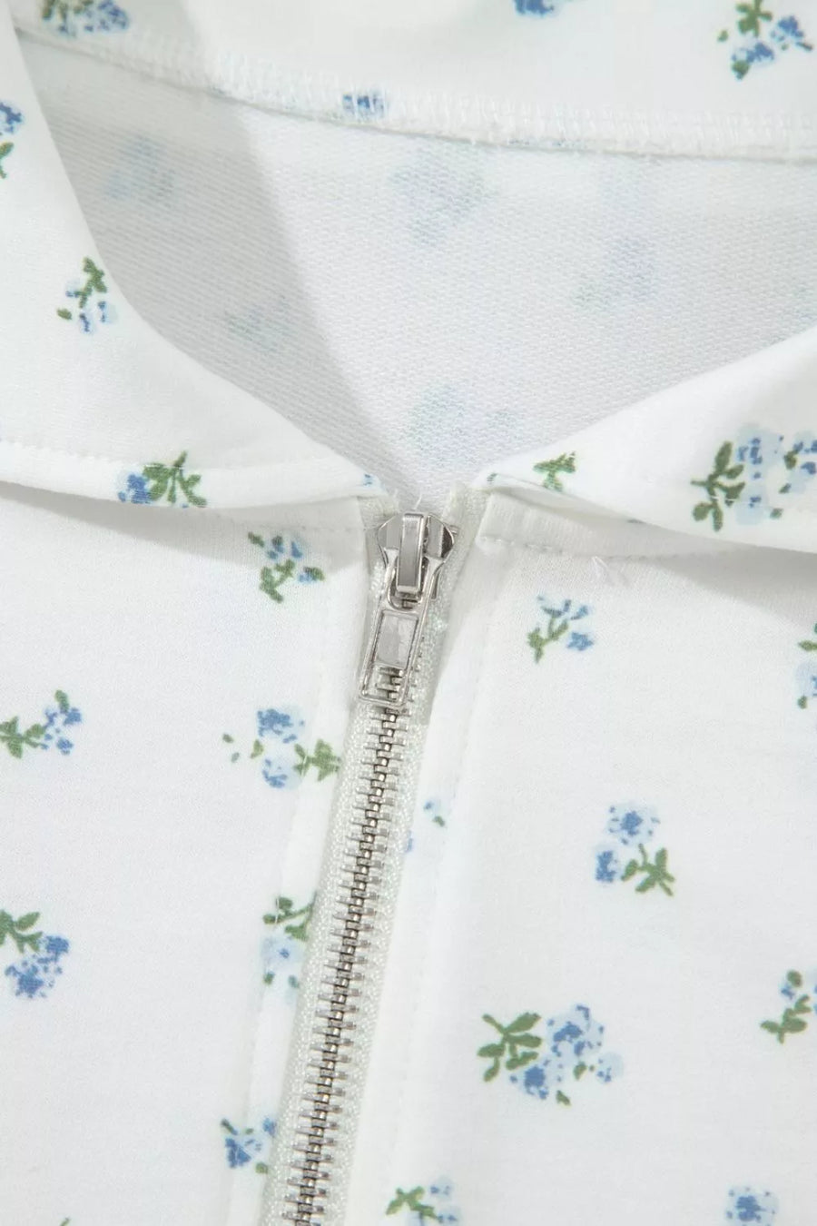 White zip-up top with a blue floral print and collar