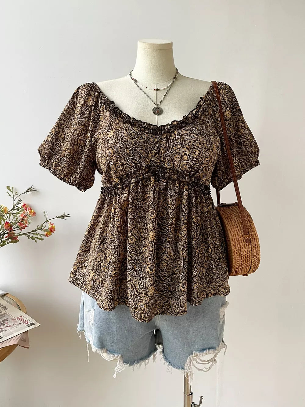Plus size coffee brown paisley print blouse with ruffled neckline and short sleeves.