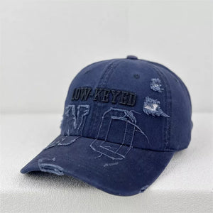Navy distressed baseball cap with embroidered "LOW-KEYED" text and frayed details.