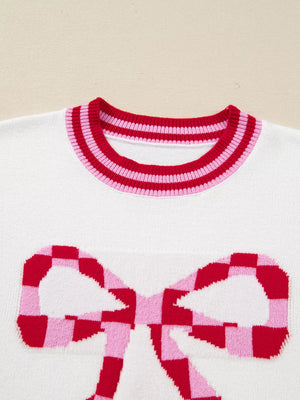 White sweater with red and pink checkered bow graphic and striped neckline.