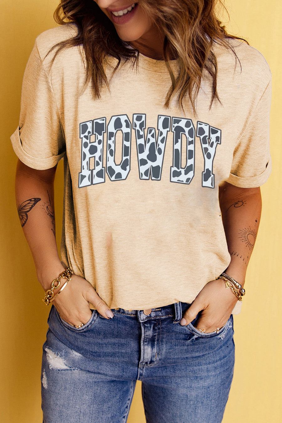 Light apricot t-shirt with cow print "Howdy" graphic and rolled sleeves.