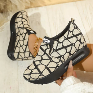 Beige and black geometric patterned slip-on sneakers with a platform sole.