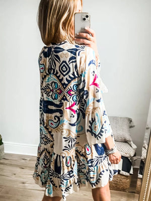Vibrant tiered mini dress with abstract print, button detail, and bell sleeves.