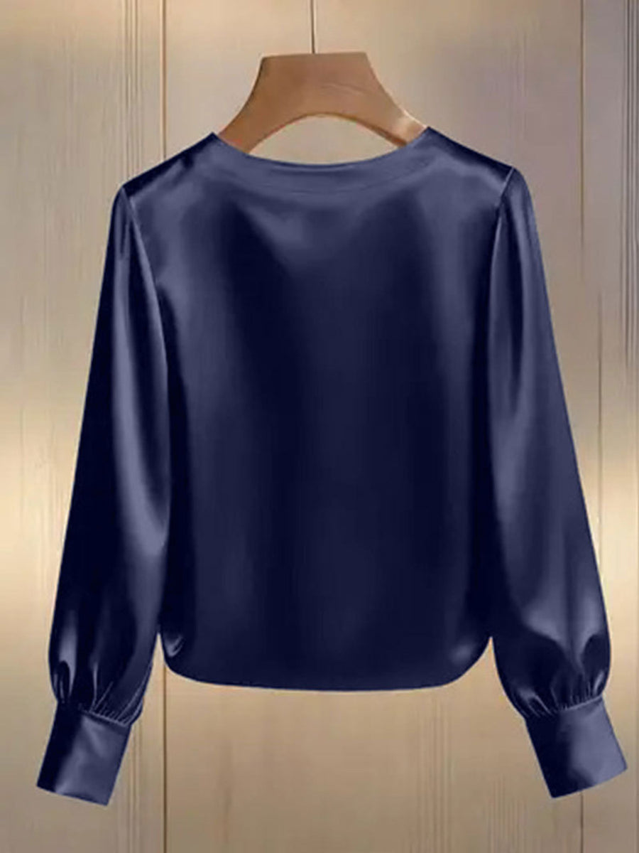 Dark blue satin blouse with round neck and long puff sleeves with cuffs.