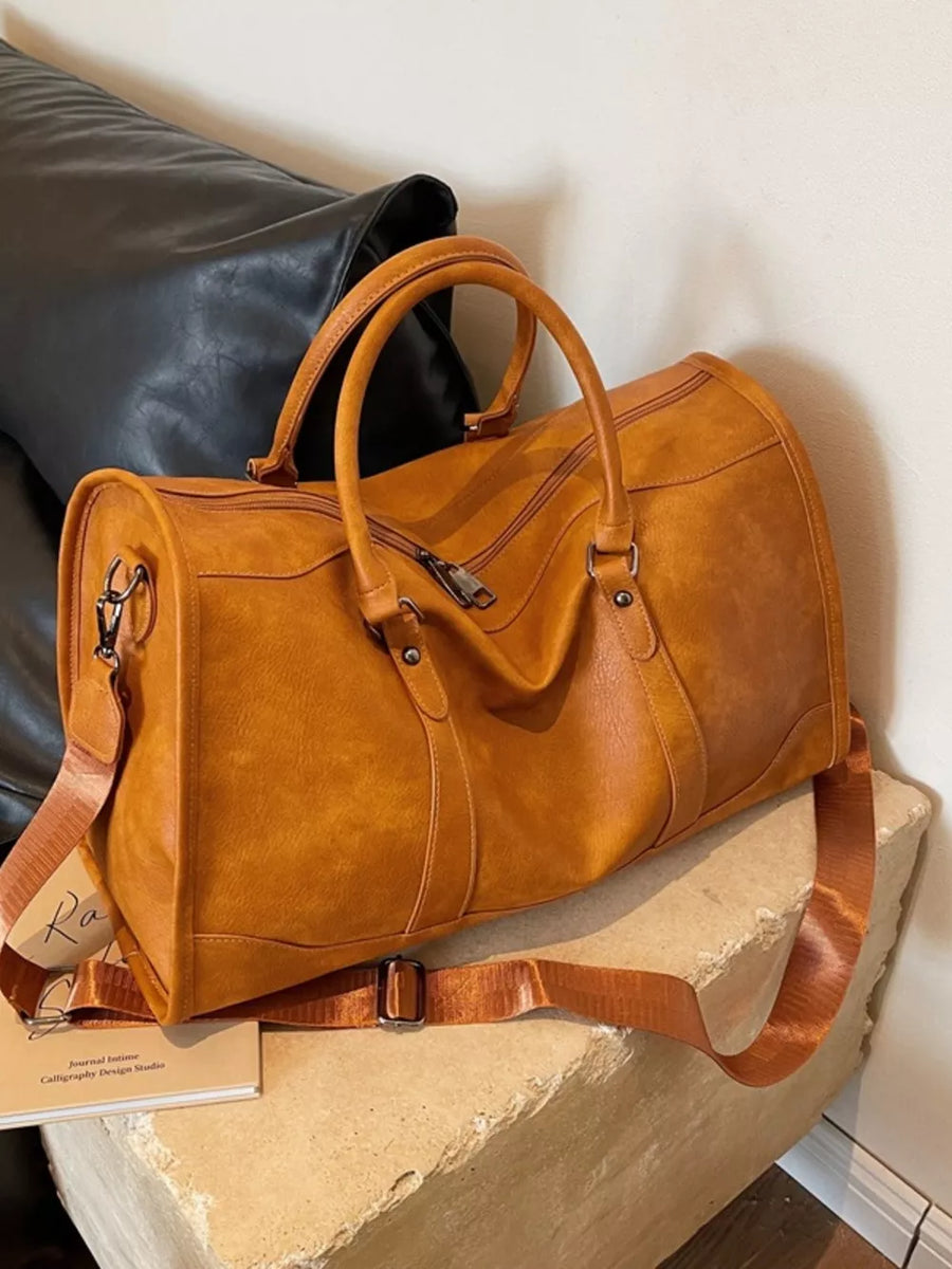 Cognac vintage leather duffle bag with top handles and adjustable shoulder strap.