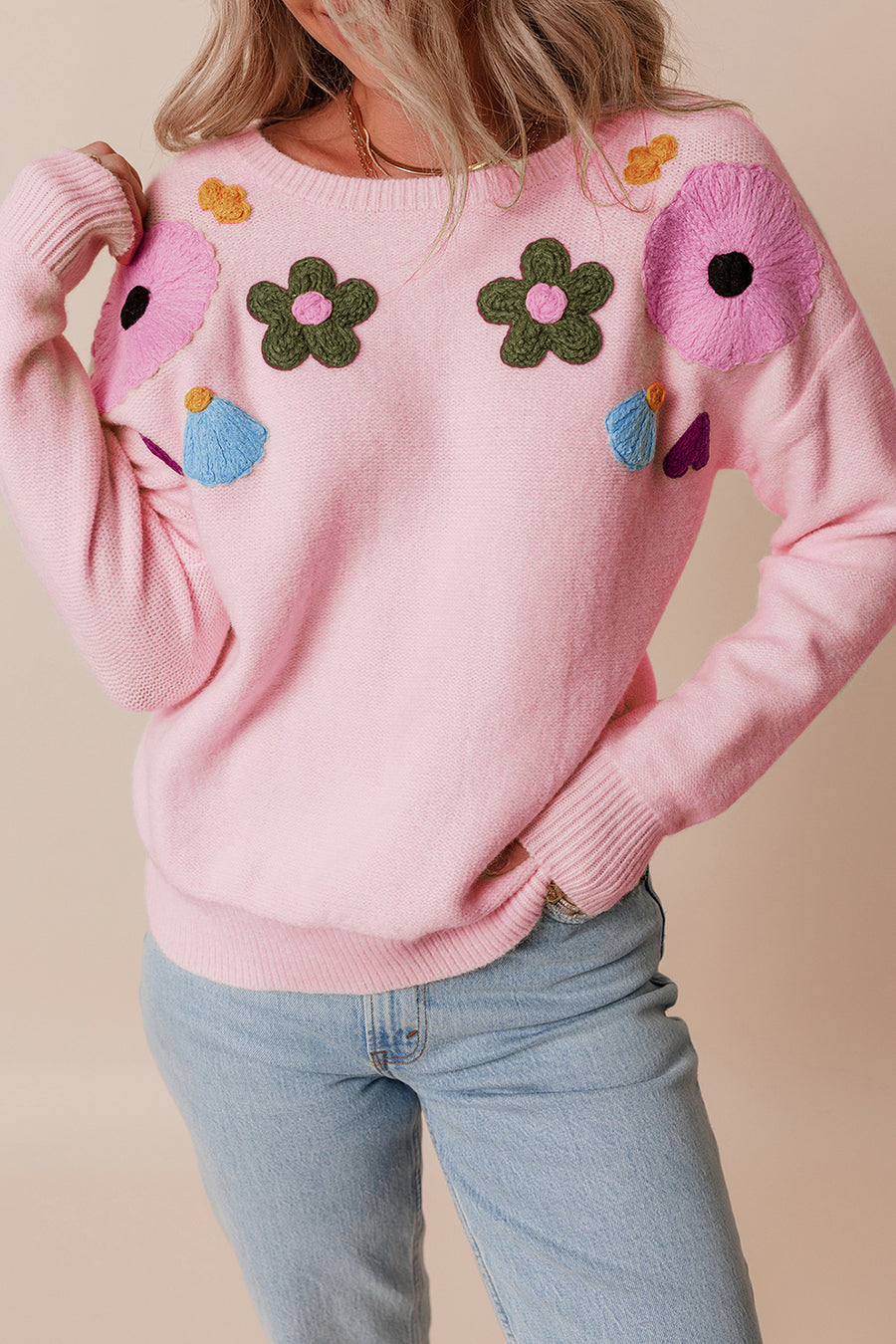 Blush pink knit sweater with embroidered floral appliqués and crewneck.