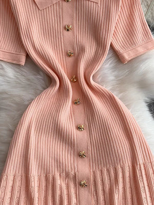 Pink ribbed knit midi dress with collar and gold bow buttons.
