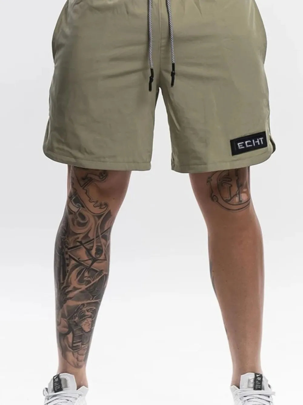 Khaki performance drawstring shorts with black logo patch and white drawstring.