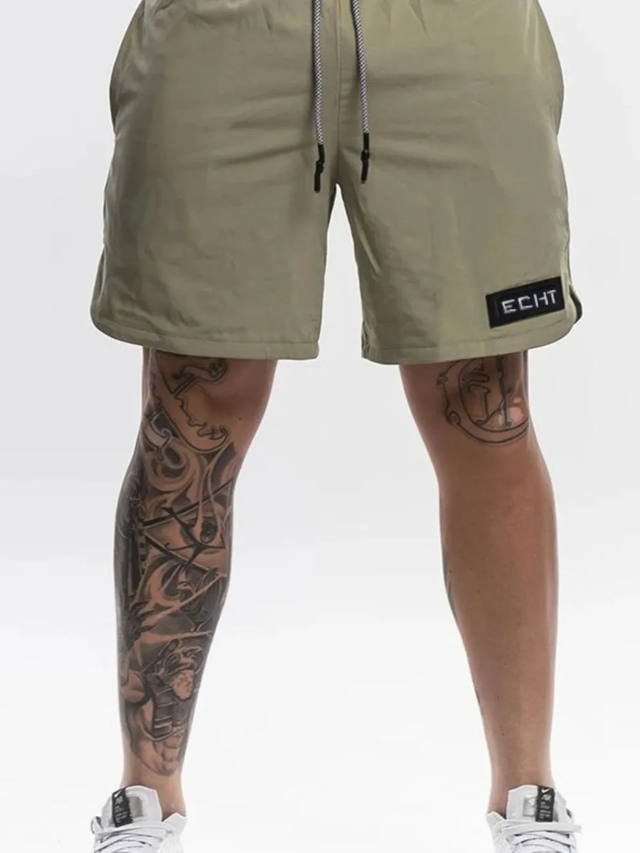 Khaki performance drawstring shorts with black logo patch and white drawstring.