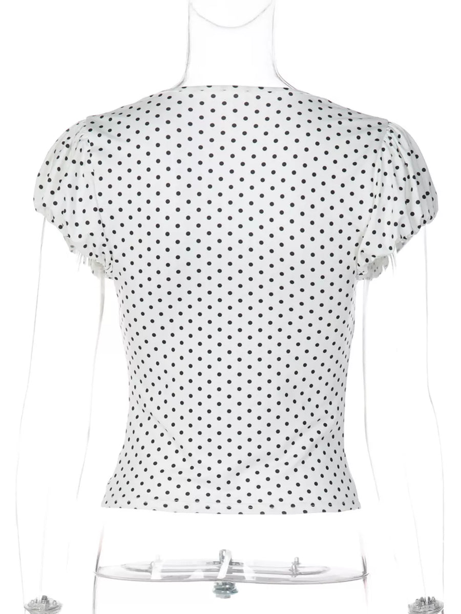 White polka dot ruched t-shirt with short sleeves and a V-neckline.