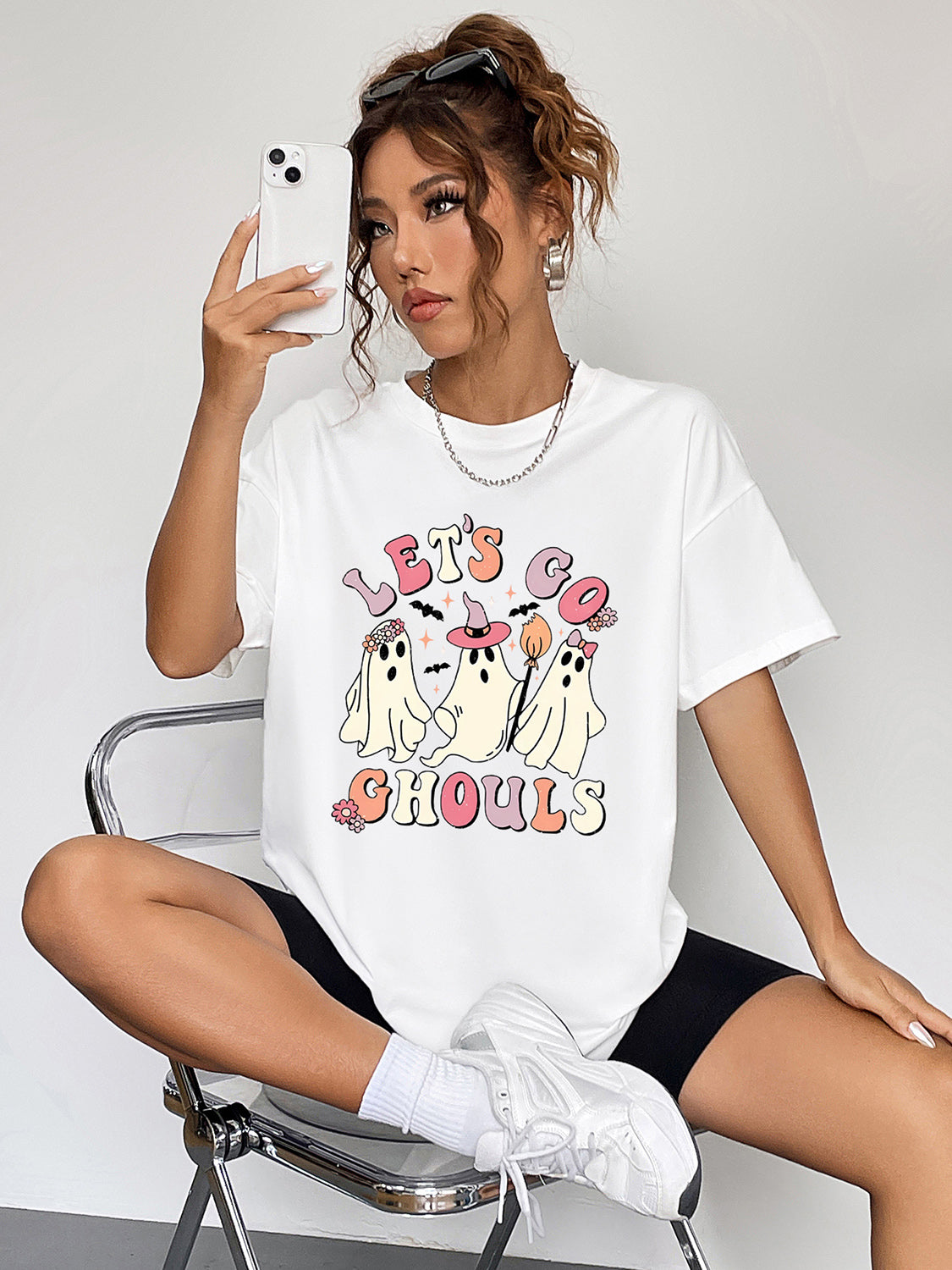 White graphic t-shirt with retro ghosts and "Let's Go Ghouls" text, crew neck, short sleeves.