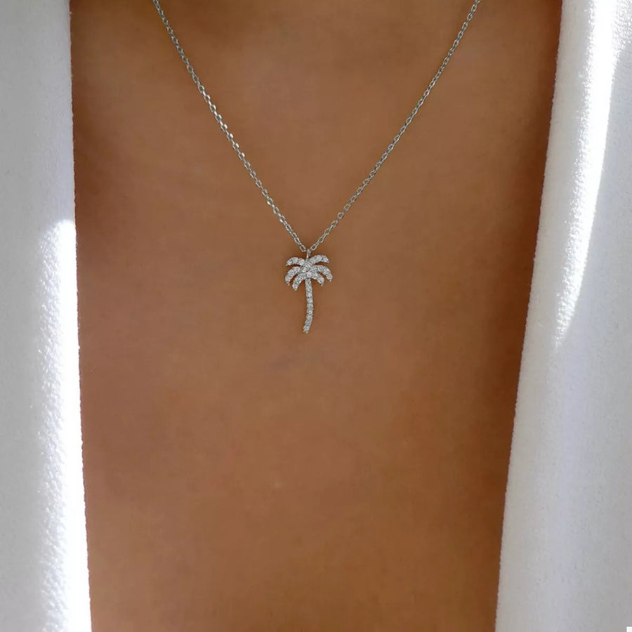 Silver palm tree pendant necklace with crystal accents on a delicate chain.