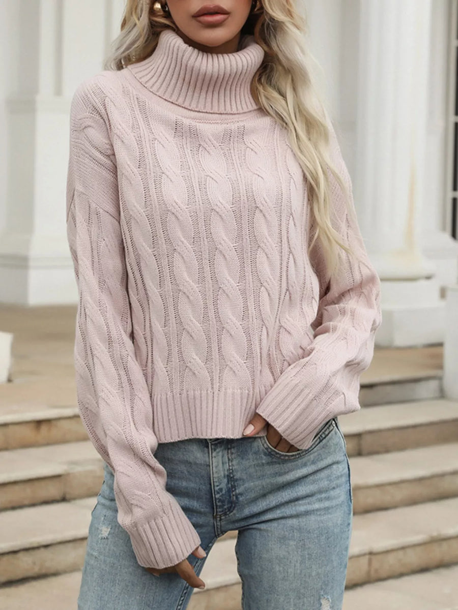 Pink cable knit turtleneck sweater with ribbed cuffs and hem.