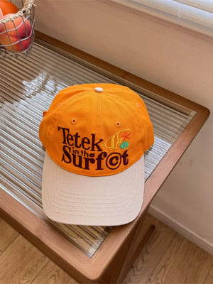 Orange and beige cotton baseball cap with embroidered text and graphics.