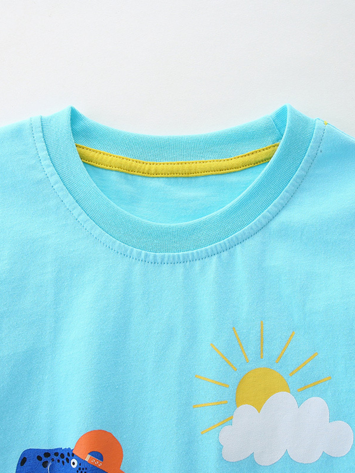 Toddler blue t-shirt with dinosaur and sun graphic, yellow neck trim