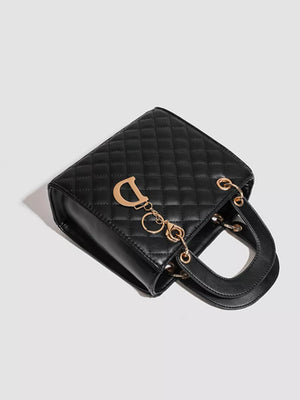 Mini quilted top-handle tote in black with gold hardware and a decorative charm.