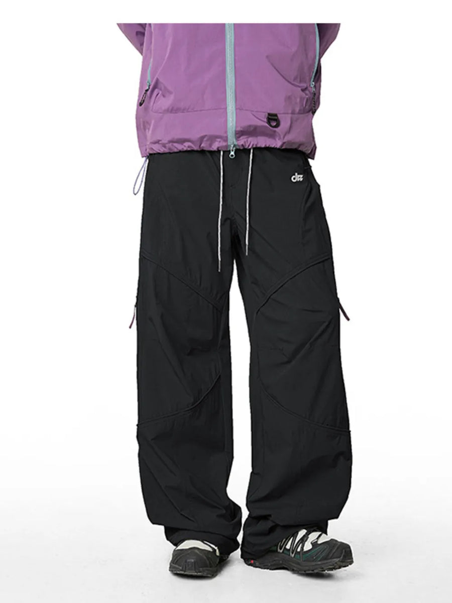 Relaxed fit black cargo pants with drawstring and zippered pockets, styled with a purple jacket.